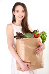 Isolated woman holding a shopping bag full of vegetables on white background