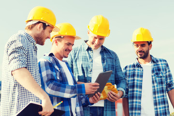 group of smiling builders with tablet pc outdoors