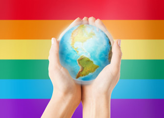 close up of hands with earth globe over rainbow