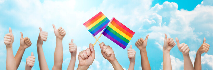 hands showing thumbs up and holding rainbow flags
