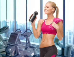 happy woman drinking water from bottle in gym