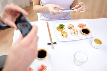 Obraz na płótnie Canvas close up of couple with smartphones at restaurant