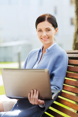 smiling business woman with laptop in city