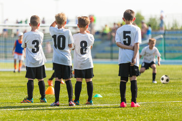 Fototapeta premium Football soccer match for children. Kids waiting on a bench.