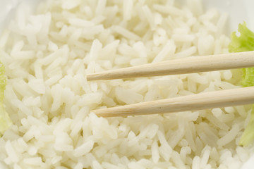 White plate of cooked long-grain rice on wooden background. Healthy eating, diet, vegetarianism.