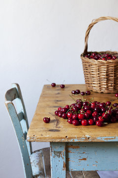 Freshly picked cherries in a basket and on rustic kitchen table