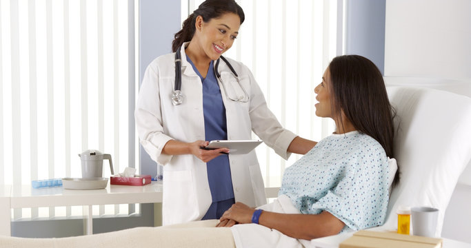 Hispanic female doctor talking to African patient