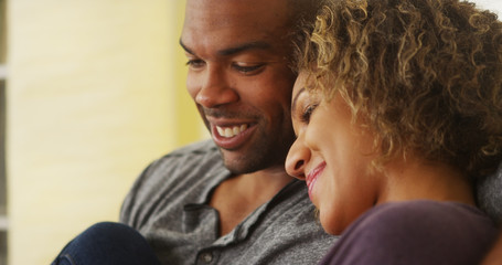 Black couple sitting on couch smiling