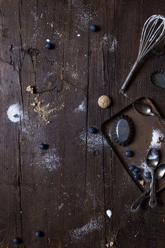 Aged wood surface with kitchen used tools and sprinkled with ingredients