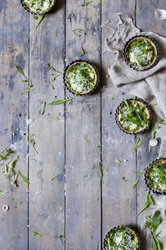 group of little quiche with green fresh vegetables and Parmesan cheese on wooden table