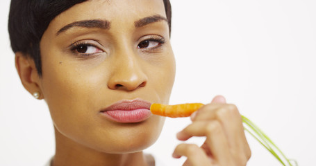 Close up of black woman eating carrot on white background