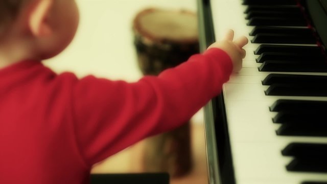 A cute toddler playing a black piano