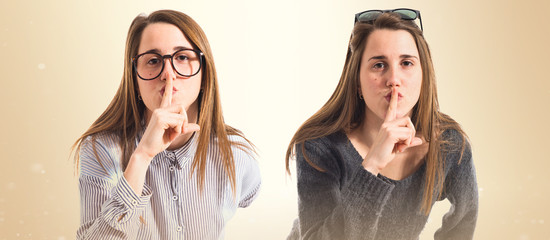 Twin sisters making silence gesture