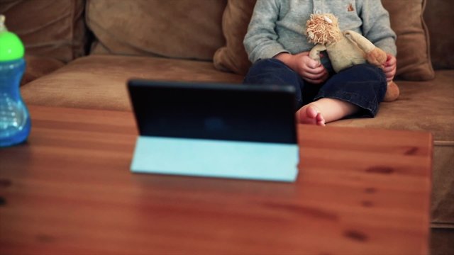 a cute toddler boy watching a movie on a tablet