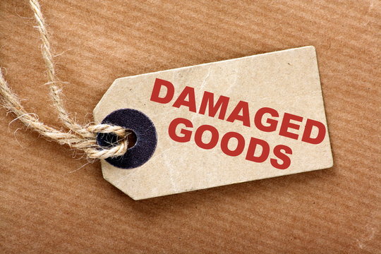 The description Damaged Goods on a luggage tag or price ticket on brown wrapping or parcel paper