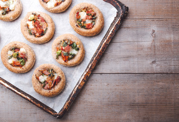 Mini pizzas on a baking paper in a pan