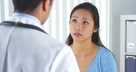 Obraz premium Chinese patient talking to doctor about neck pain