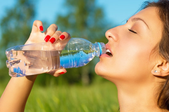 Woman drinks water from a bottle outdoor summer