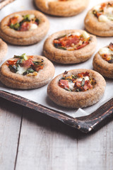 Mini pizzas on a baking paper in a pan