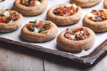 Mini pizzas on a baking paper in a pan