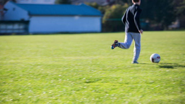 Boy on soccer field running with ball
