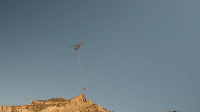 Helicopter carrying construction supplies through mountains