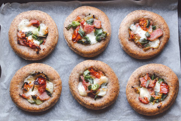 Mini pizzas on a baking paper in a pan