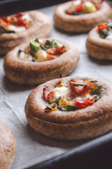 Mini pizzas on a baking paper in a pan