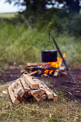 Bundle of firewood on a background of a bonfire with pot