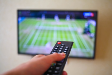 Hand with the remote control, front of the television.
