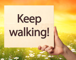 Female hand holding a card with text: Keep walking