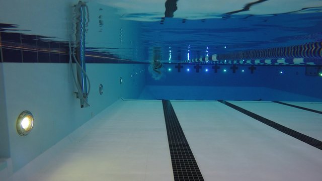 Underwater pool shot of a man swimming toward camera