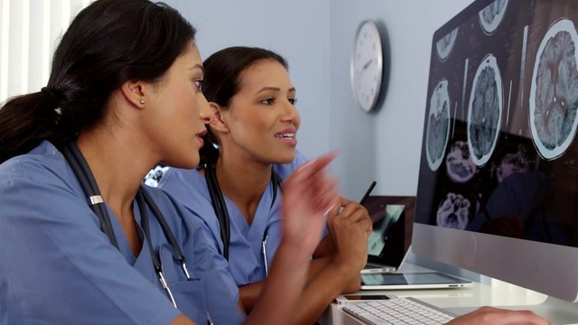 Two doctors reviewing brain scans on hospital computers