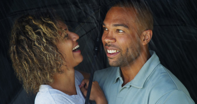 African Couple Laughing Under Umbrella Together