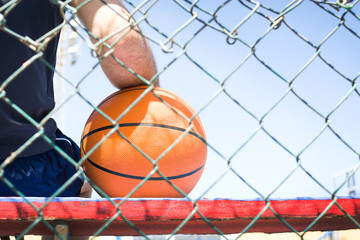 young man with a basketball behind a fence