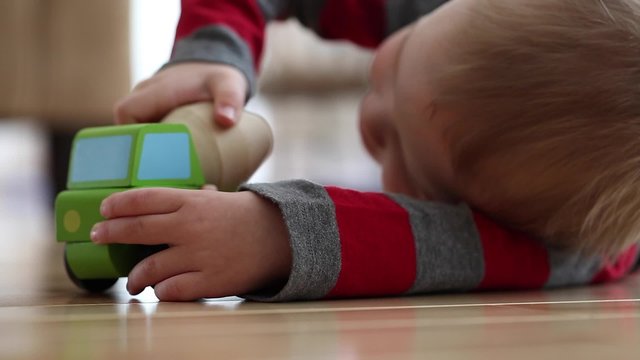 little boy plays with toy wood truck