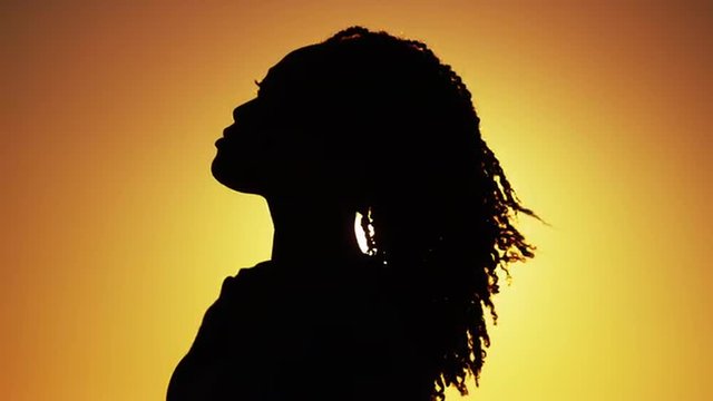 Silhouette of Black woman standing at sunset