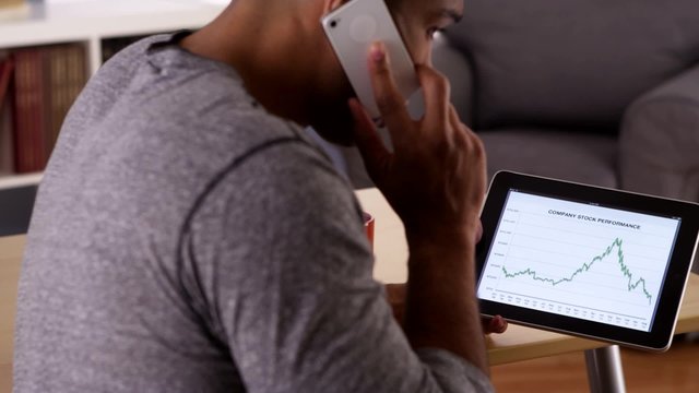 African businessman talking on smartphone while looking at graphs