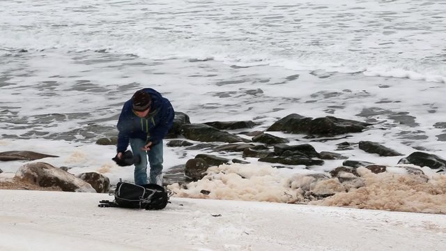 photographer taking pictures of ocean in snowstorm