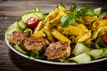 Pasta with pesto sauce, fried chops, parmesan and vegetables 