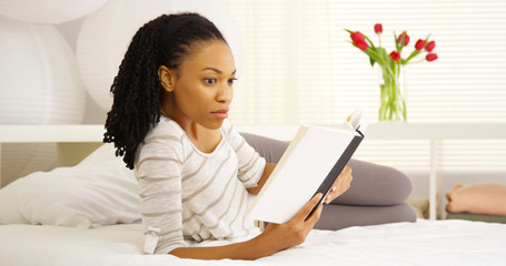 Obraz na płótnie Canvas Black woman reading on bed