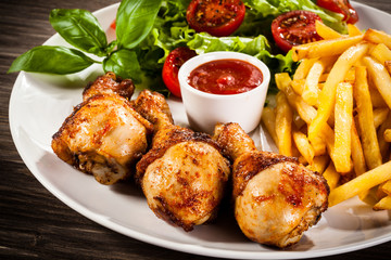 Grilled chicken legs with chips and vegetables 
