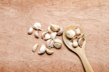 garlic cloves on wooden spoon and scattered on the wooden floor