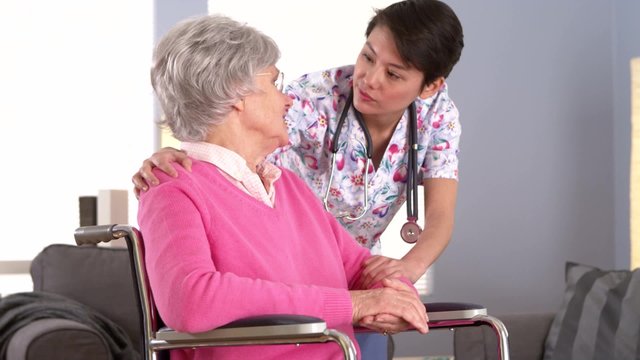 Elderly patient talking to caring Asian nurse