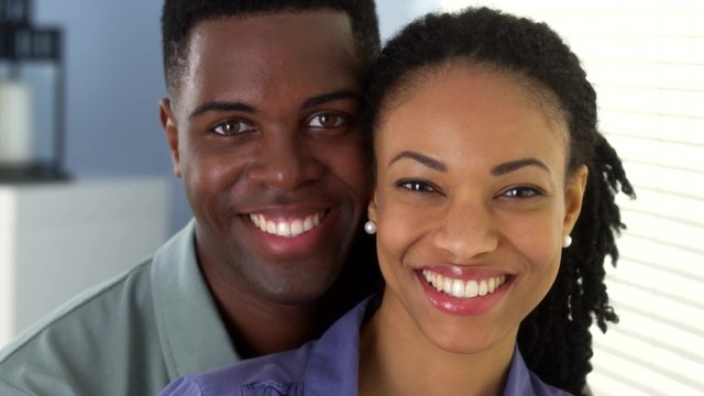 Portrait of young black couple holding each other looking at camera