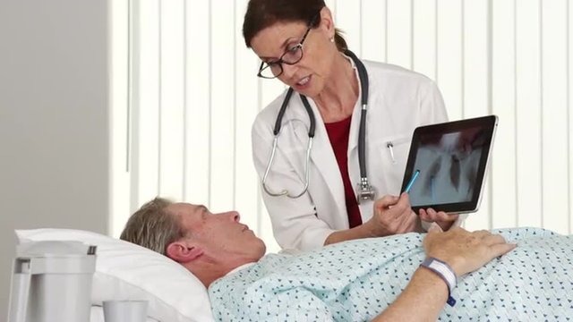 Senior woman doctor talking to elderly patient lying in bed