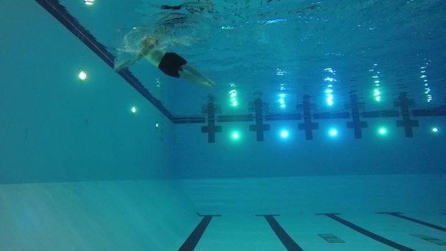 Slow motion of swimmer exiting pool underwater side shot