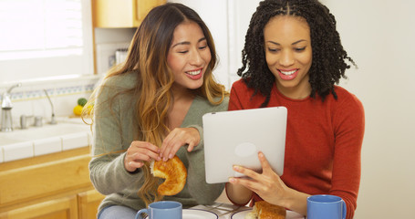 Two women best friends eating breakfast and using tablet computer