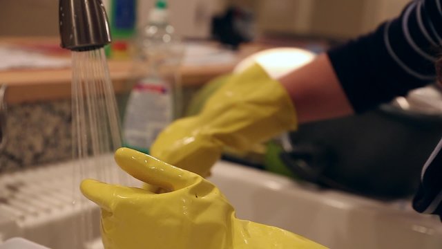pregnant mother washing dishes in the kitchen sink
