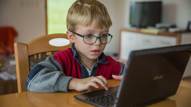 Sliding towards kid on laptop computer at home